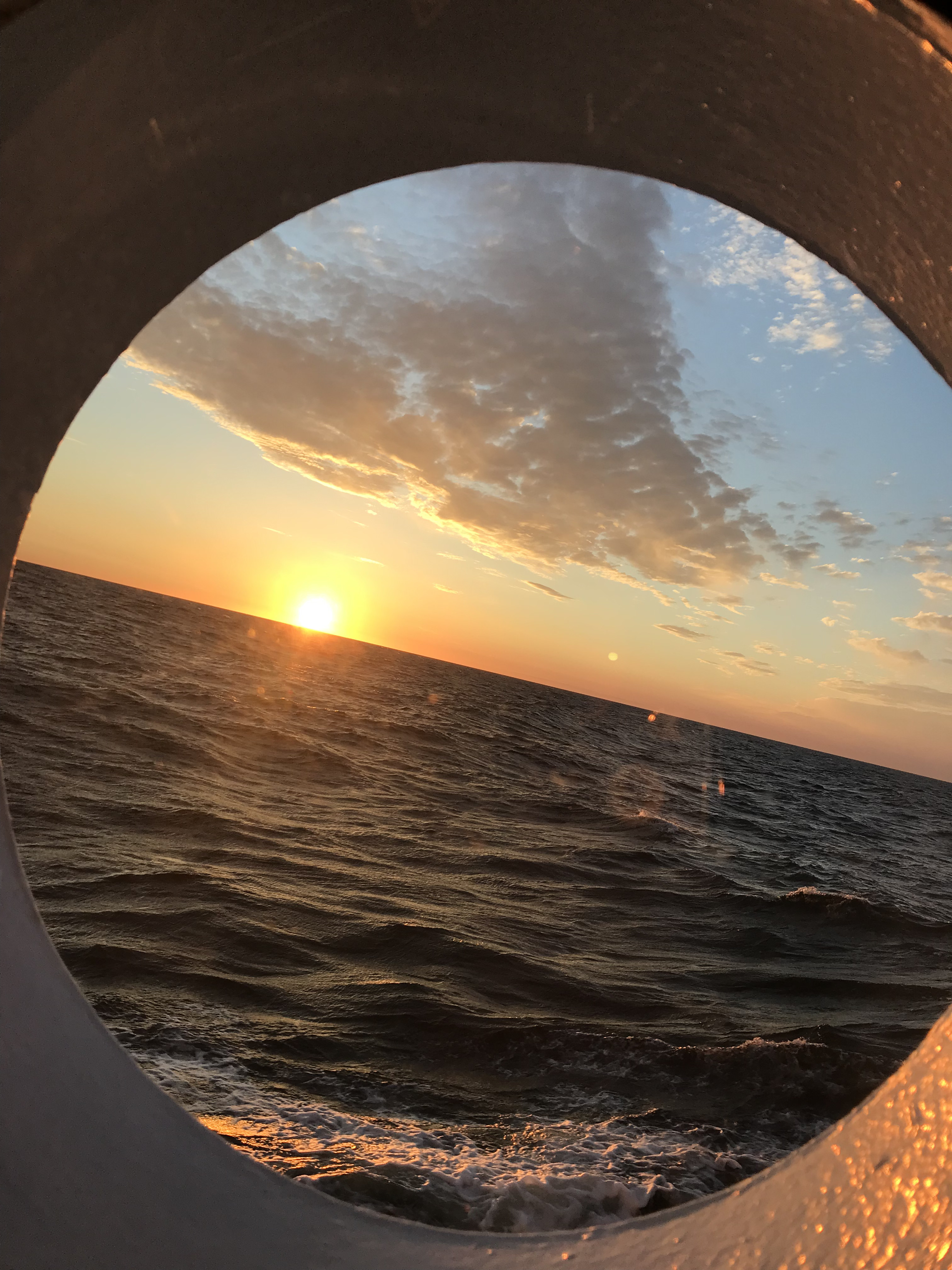 Sonnenuntergang auf dem Meer durch ein Bullauge